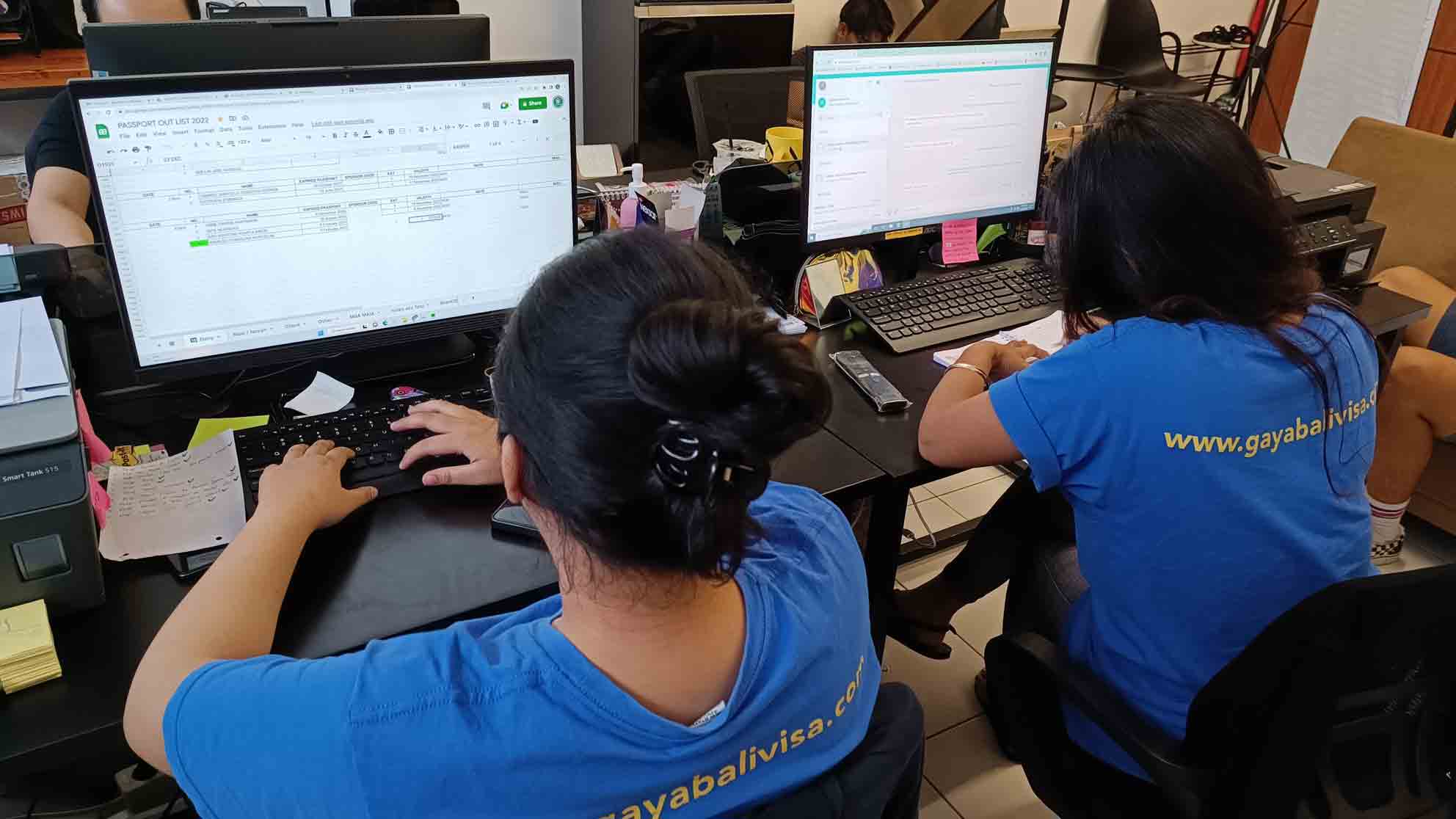 Picture of Oca and Delsi staff of Gaya Bali Visa working on computer